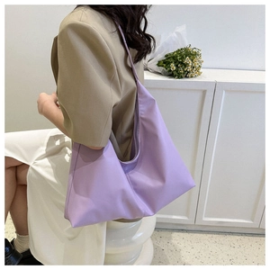 Detailed side view of light purple hobo tote bag worn with a beige blazer jacket
