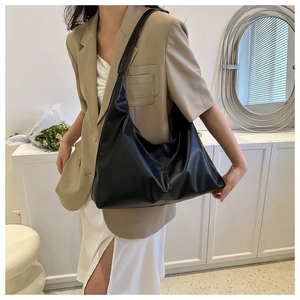 Detail of a large black faux leather hobo shoulder bag with vertical stitching and wide strap