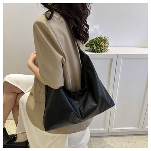Side view of a black minimalist large capacity PU leather tote bag worn by a model