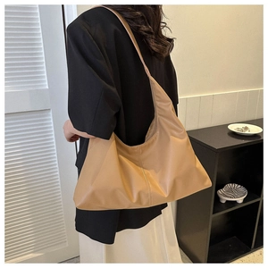 Detail of a large khaki hobo bag with smooth texture worn by a model in a minimal setting