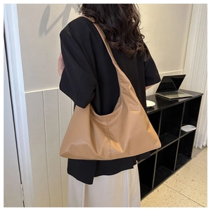 Detail of the camel brown Hobo shoulder bag worn by a model in a minimalist urban style
