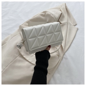 Détail d'un sac bandoulière rectangulaire blanc avec texture géométrique à triangles