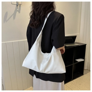 Detail view of a white soft PU leather hobo bag worn by a model in a minimalist setting