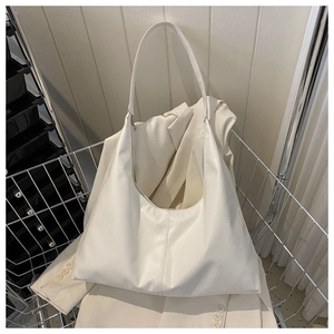 Detail of minimalist cream PU leather tote bag with vertical stitching in a metal cart