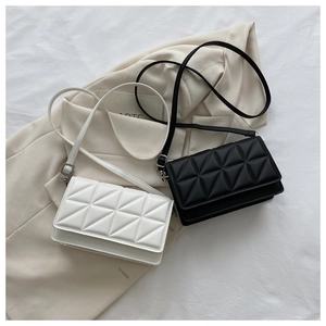Détail de sacs bandoulière matelassés classiques noir et beige sur un blazer neutre