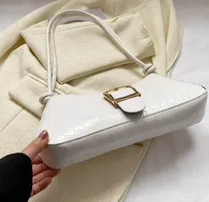 Détails de la texture crocodile blanche et boucle dorée sur ce sac baguette tendance