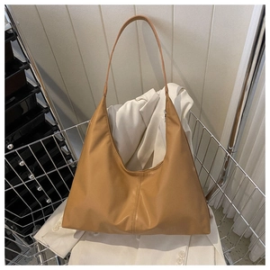 Hobo style caramel faux leather tote bag with vertical stitching on a display stand