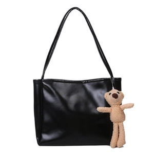 Minimalist black leather tote bag for women with cute teddy bear charm on white background