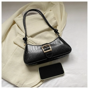 Détail du sac noir à texture croco avec boucle dorée à côté d'un téléphone pour référence