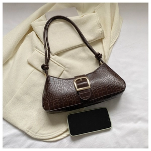 Détail du sac baguette marron à texture crocodile avec boucle dorée et téléphone pour taille