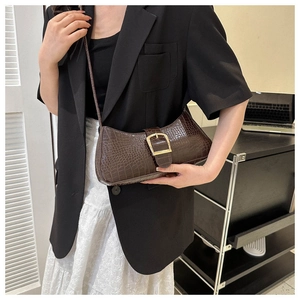Détail du sac sous l'aisselle marron foncé à texture crocodile et boucle dorée sur modèle