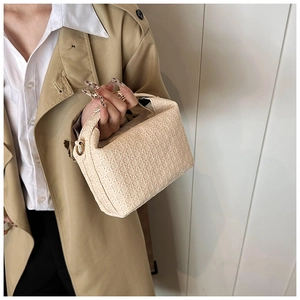 Detail of beige woven handbag texture with golden D-ring and elegant model styling