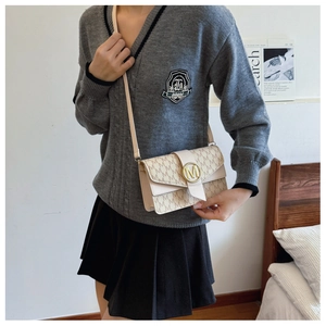 Detailed view of beige monogram underarm bag with gold M buckle on a model