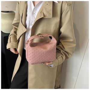 Detailed view of a pink woven handbag with a gold square clasp on a khaki coat background
