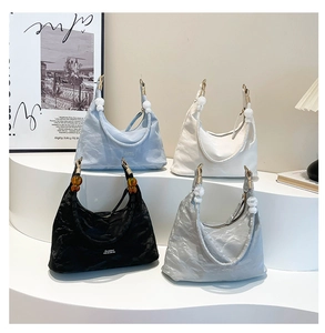 Minimalist hobo bags in blue, white, black and silver with beaded straps on white podiums
