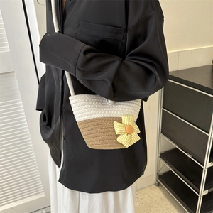 Chic woven beach bag with contrast stitching, pearl buckle, and floral charm detail