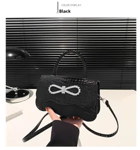 Detail of black crocodile texture handbag with a silver rhinestone bow buckle accent