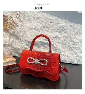 Detail of red crocodile pattern handbag featuring a sparkling rhinestone bow decoration