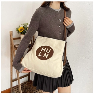 Detail of canvas tote bag showing brown leather strap and silver metal hardware
