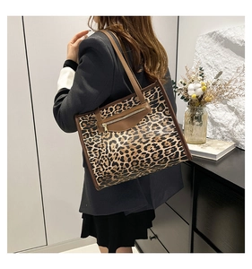 Detail view of large leopard print tote bag with brown trim and front zipper pocket