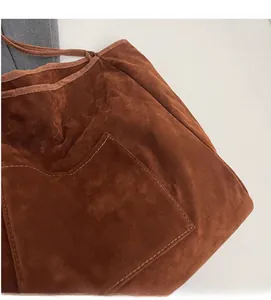 Detailed macro view of brown suede tote bag featuring fine stitching and outer pocket