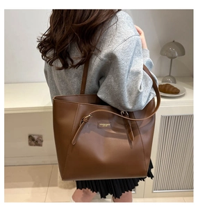 Detail of caramel brown PU leather tote bag featuring decorative buckle and fashion logo