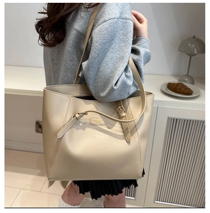Minimalist beige tote bag shown over the shoulder in a cozy lifestyle setting
