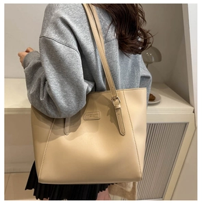 Detail of adjustable strap and leather logo patch on large beige tote bag