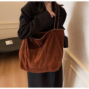 Detail of vintage brown suede tote bag featuring a front pocket and thin shoulder strap