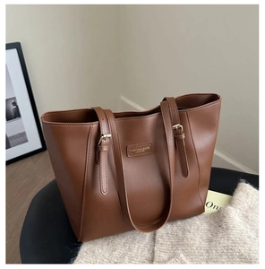 Detail of adjustable strap and golden buckle on a large brown leather tote bag