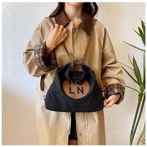 Detail of black canvas tote bag with brown leather HULN logo patch and shoulder strap