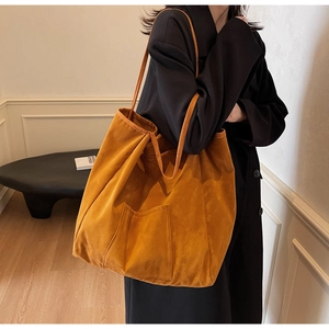 Detail of a large mustard suede tote bag shown on model for daily commuting style