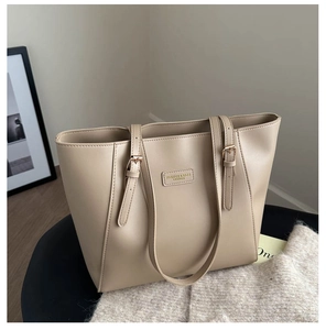 Detail of adjustable metal buckle and leather label on beige commuter tote bag