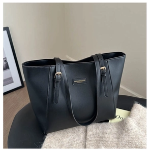 Detail of minimalist black leather tote bag with gold hardware on a stylish seat