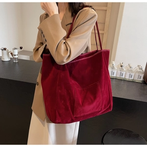Detail of burgundy velvet tote bag with exterior pocket showing shiny texture