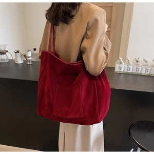 Detail of red velvet tote bag showing soft texture and exterior pocket on female model