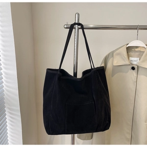 Detail of black corduroy tote bag showing the textured fabric and open front pocket