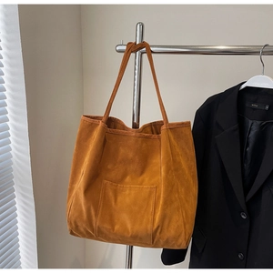Detail view of caramel suede tote bag with front pocket and slim dual handles