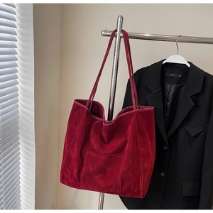 Detail of burgundy velvet tote bag with exterior pocket hanging on silver metal hanger