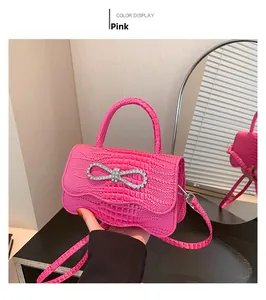 Detail of pink croc-embossed mini bag with rhinestone bow buckle and thin shoulder strap