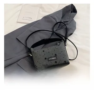 Detail of grey knitted crossbody bag with star pattern and black leather base