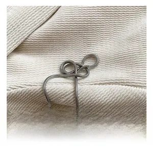 Close-up of a sleek silver snake chain strap on soft beige corduroy textured fabric
