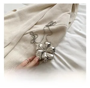 Detailed close-up of a silver flower-shaped metal clutch bag with a snake chain strap