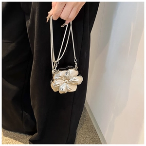 Macro detail of silver floral evening bag with metallic finish and delicate snake chain strap