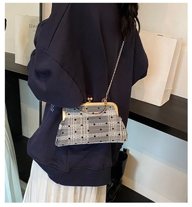 Retro grey plaid kiss-lock bag with black dots and golden chain strap on a model