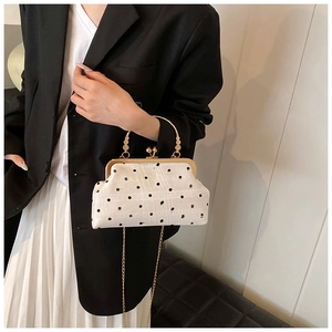 Vintage-style white and black polka dot shell bag with gold handle on fashion model
