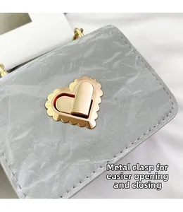 Detail of golden heart-shaped metal lock on marble textured mini handbag