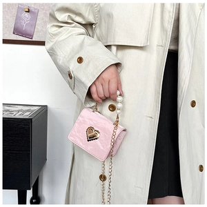 Detailed close-up of pink pleated mini bag featuring pearl handle and gold heart buckle
