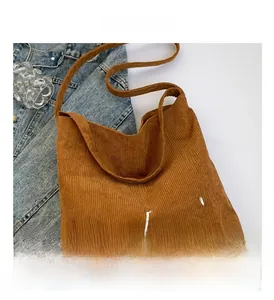 Gros plan du sac cabas en velours côtelé marron avec broderie blanche et texture douce