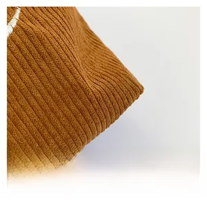 Gros plan sur la texture du velours côtelé marron et les détails de broderie blanche